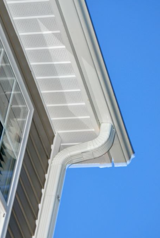 White house exterior with gutter and window against a blue sky.