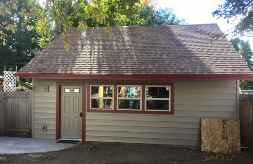 A small house with a brown roof and a lot of windows.