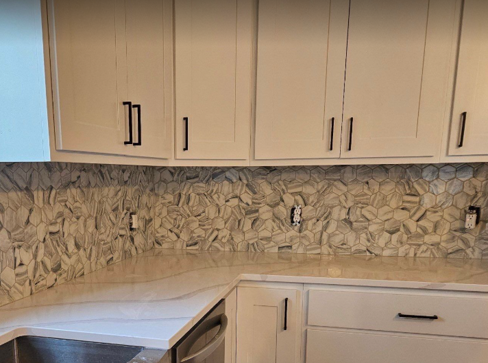A kitchen with white cabinets and a stainless steel sink.