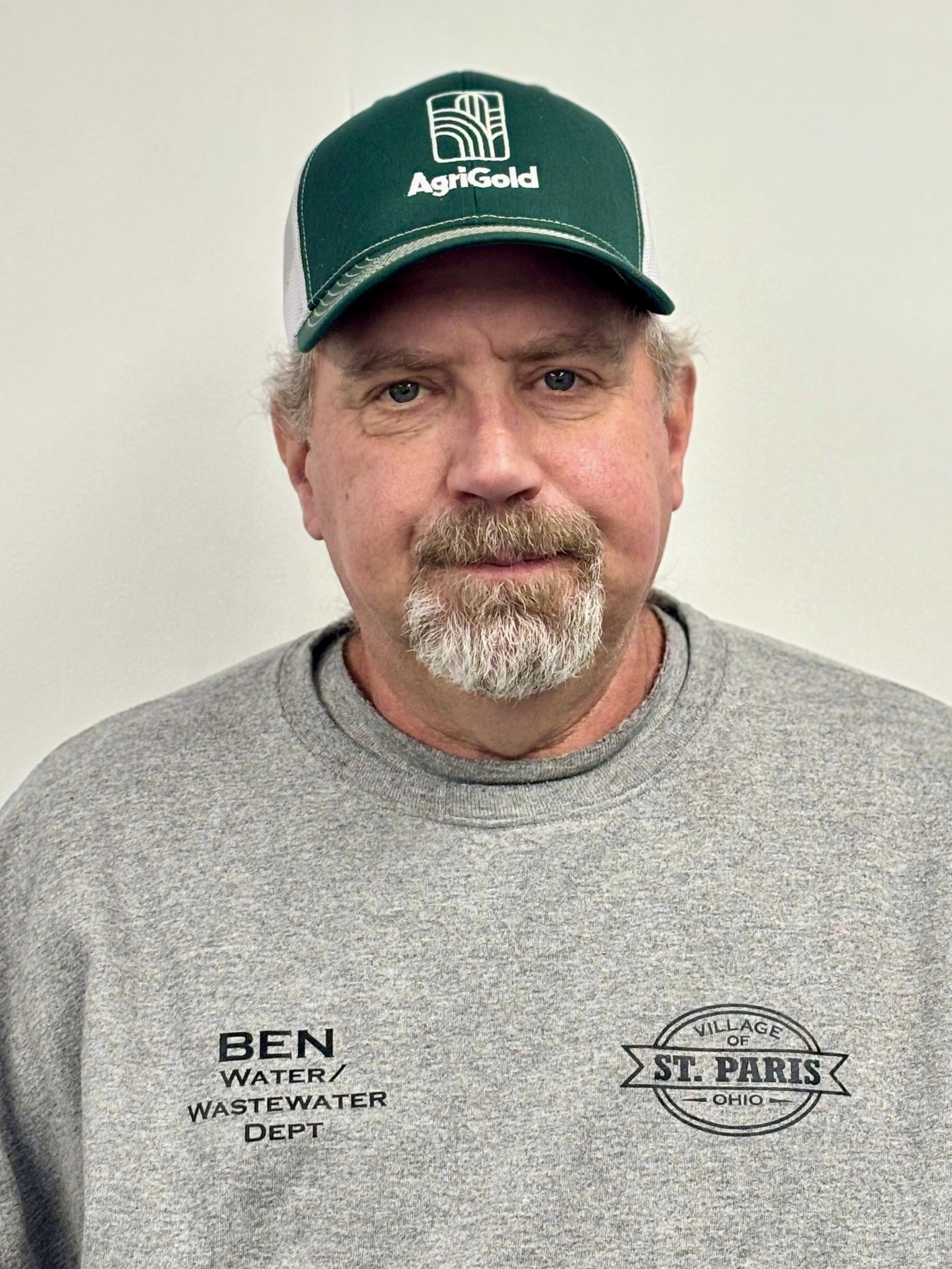 Man wearing a green and white AgriGold hat and gray sweatshirt; text on shirt reads