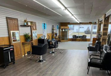 Interior of a hair salon with chairs, mirrors, and various styling stations.