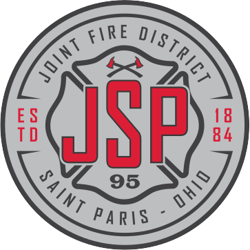 Red and white fire rescue truck parked outside a station on a sunny day.