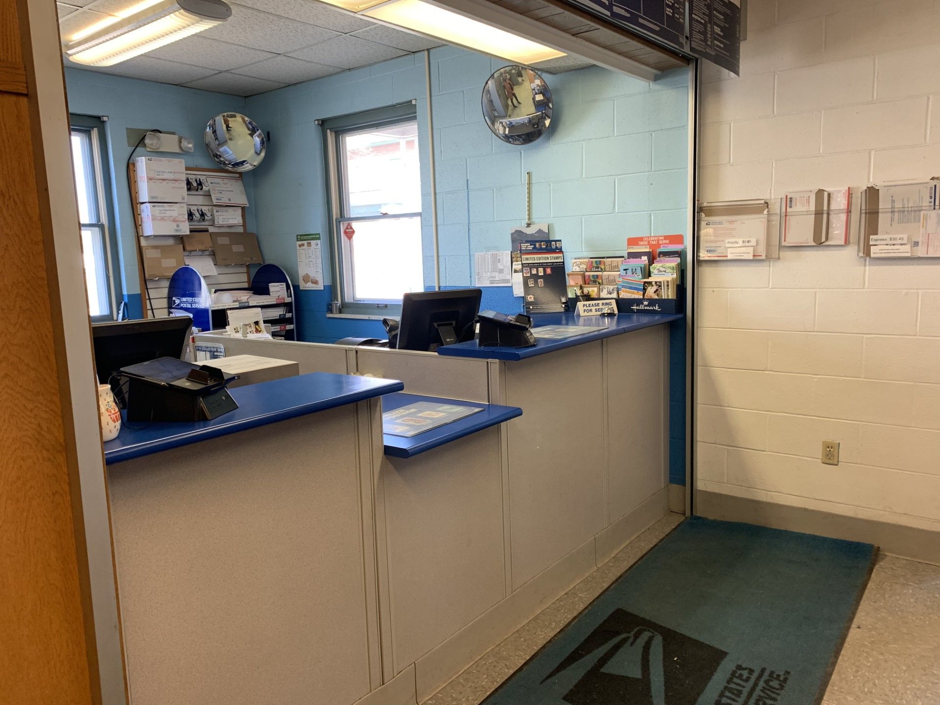 Interior of a postal service office with counter, computers, and blue and white color scheme.