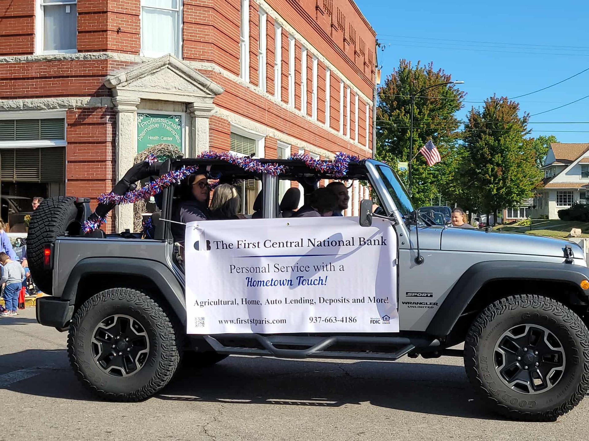 Silver Jeep in parade, banner reads: