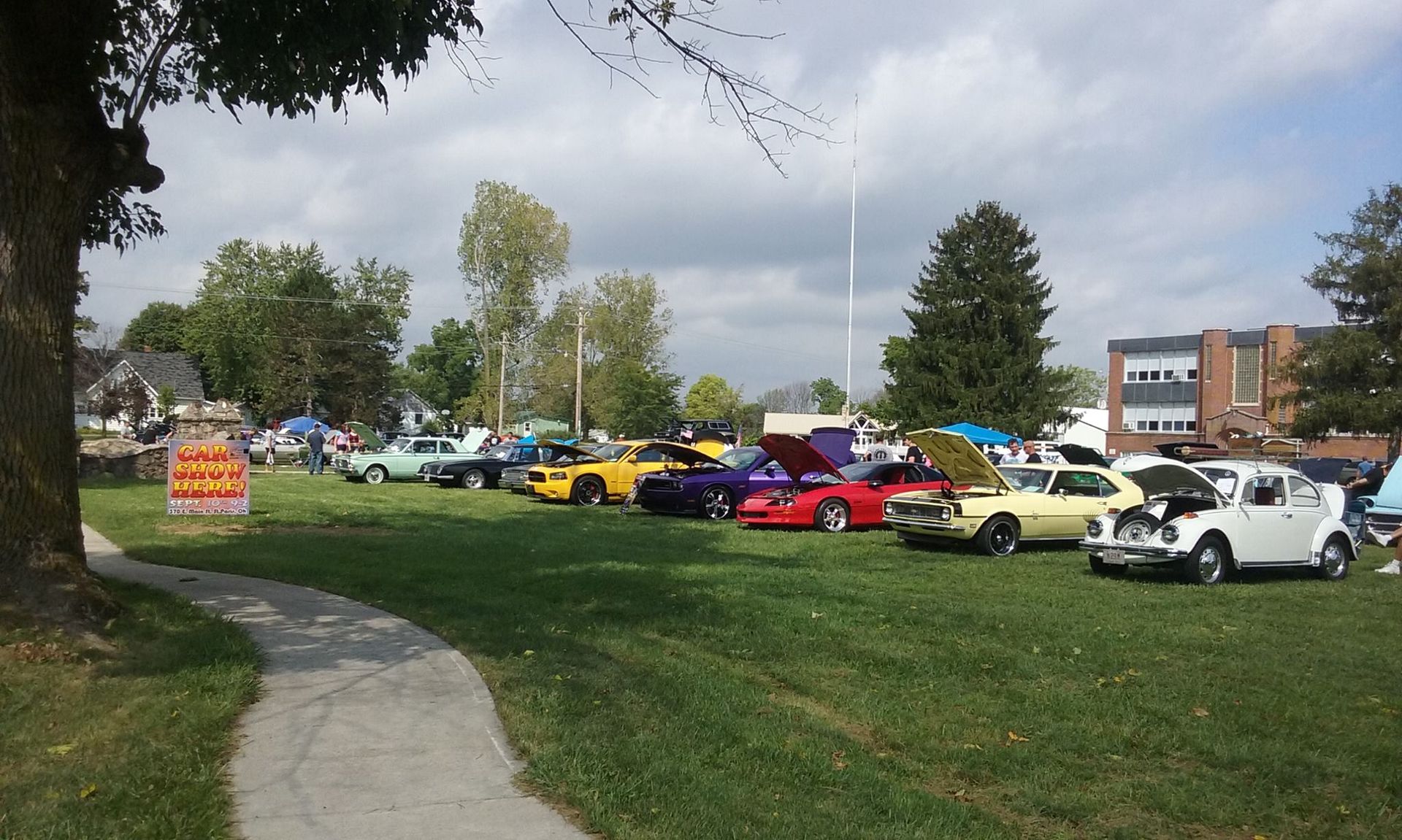Cars on display at a car show on a grassy area, sunny day.