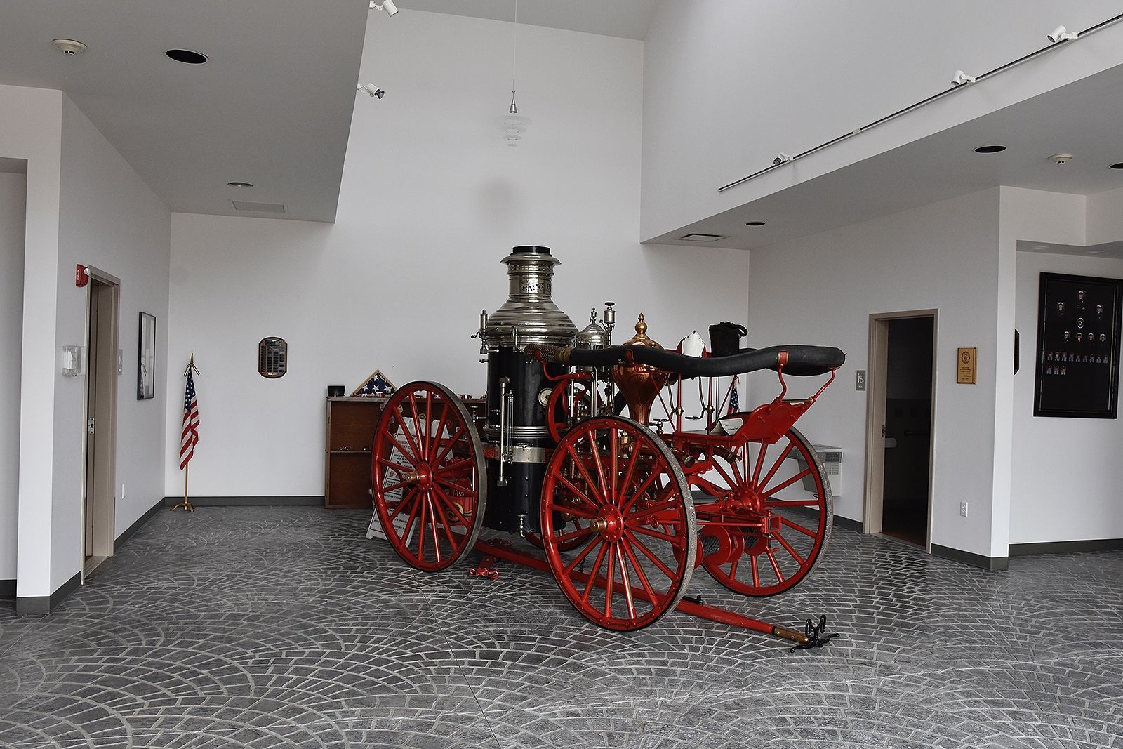 Antique red fire engine in a bright, modern room with gray patterned carpet.