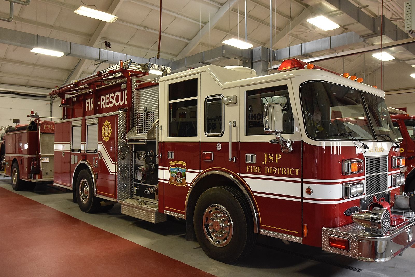 Fire truck, red and white, inside a garage. 