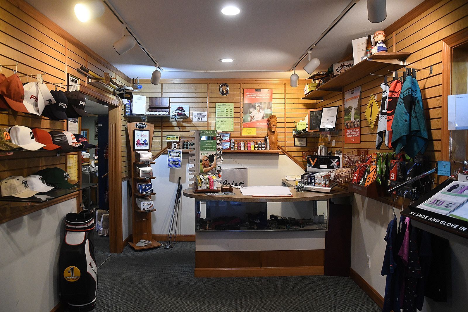 Golf pro shop interior with merchandise displays, checkout counter, and golf bag.
