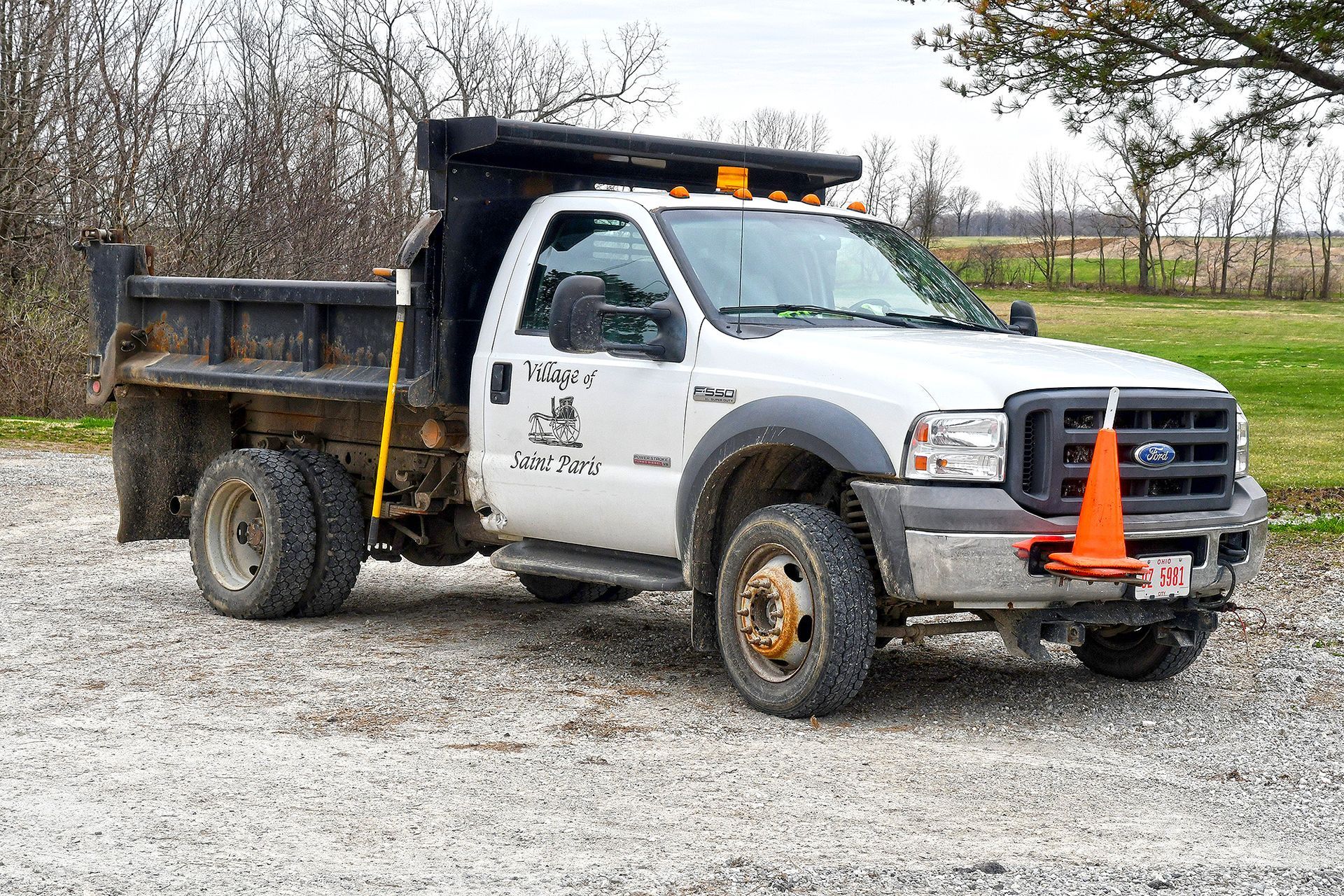White dump truck on gravel, orange cone attached to the front bumper.