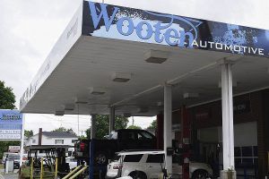 Wooten Automotive shop with vehicles on lifts. White canopy with blue logo.