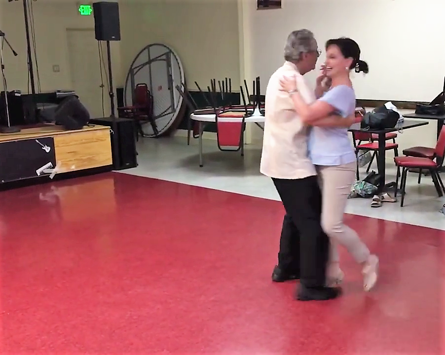 A man and a woman are dancing on a red floor