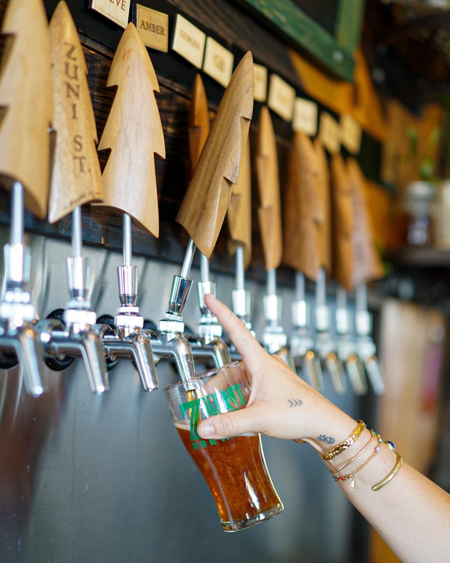 a person pouring beer from a tap that says zuni st.