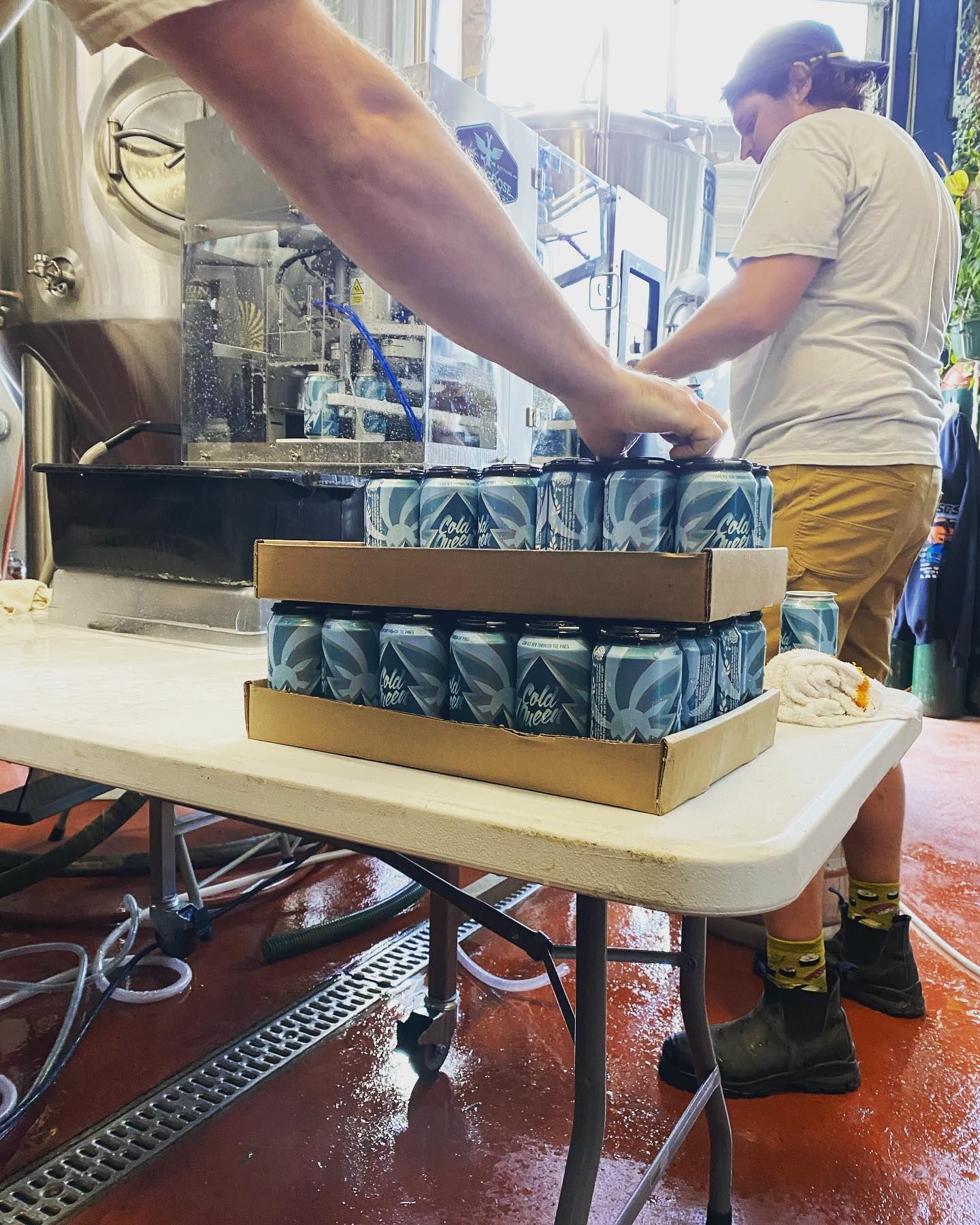 A person is stacking cans on top of each other on a table.