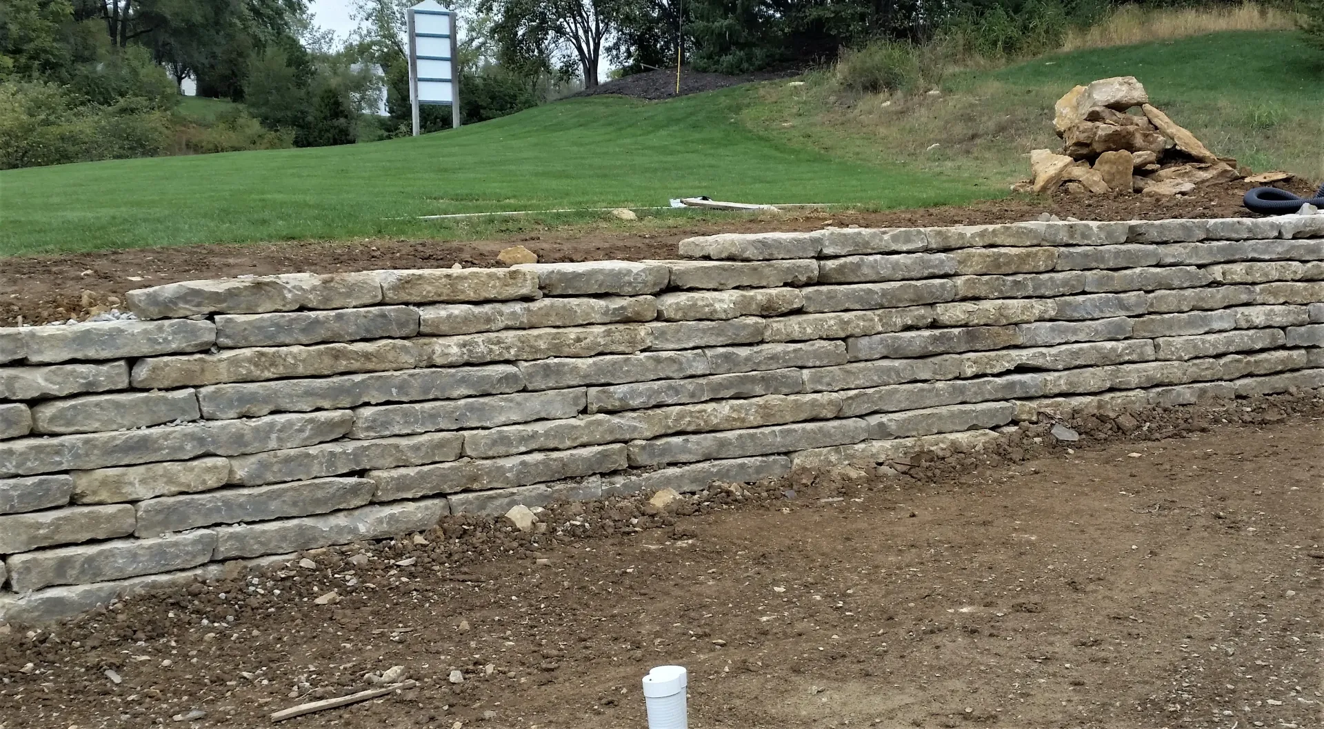 A brick wall is being built on top of a dirt field.