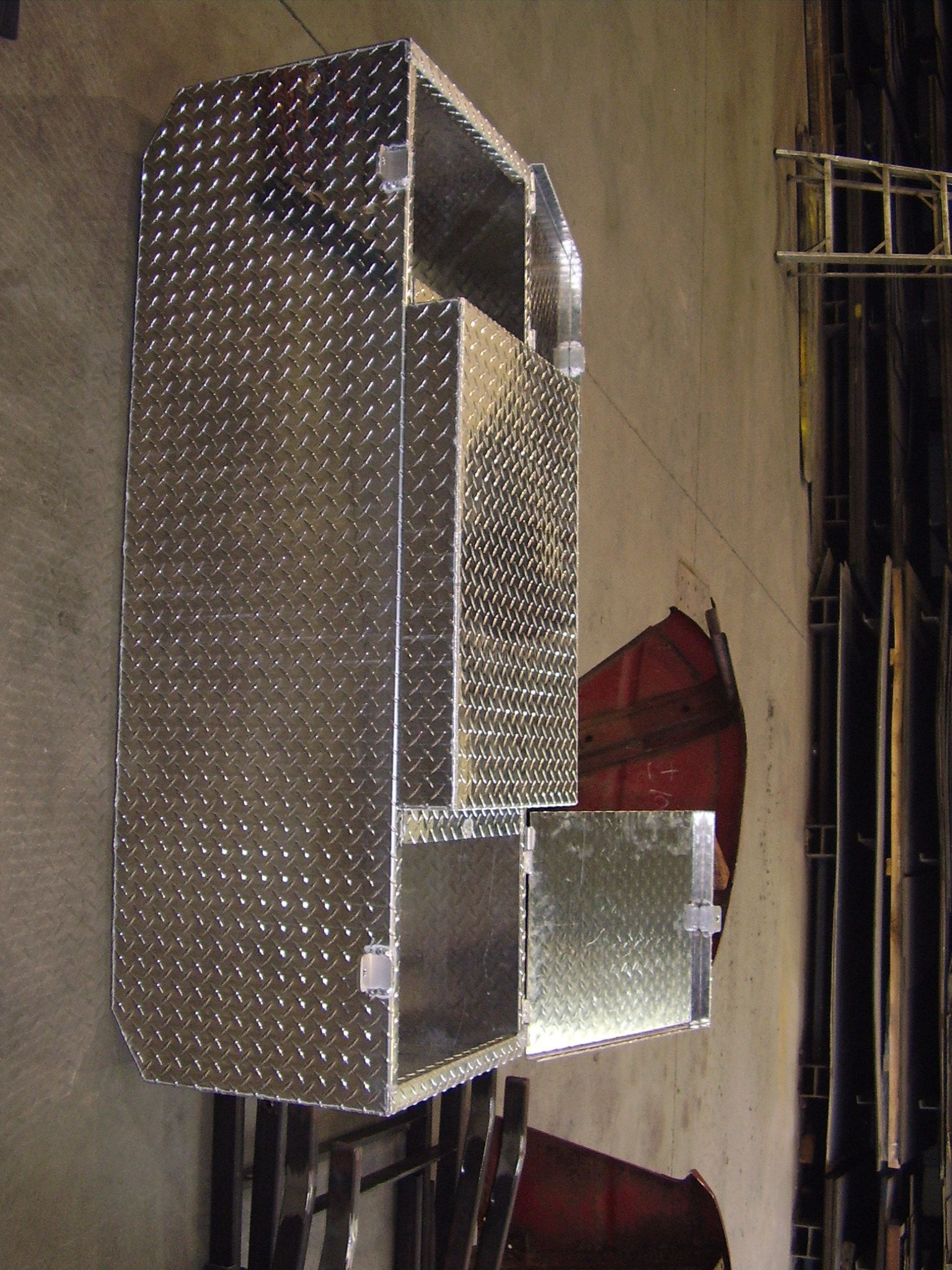 Armoire métallique en tôle larmée avec deux portes ouvertes. Fixée au mur.