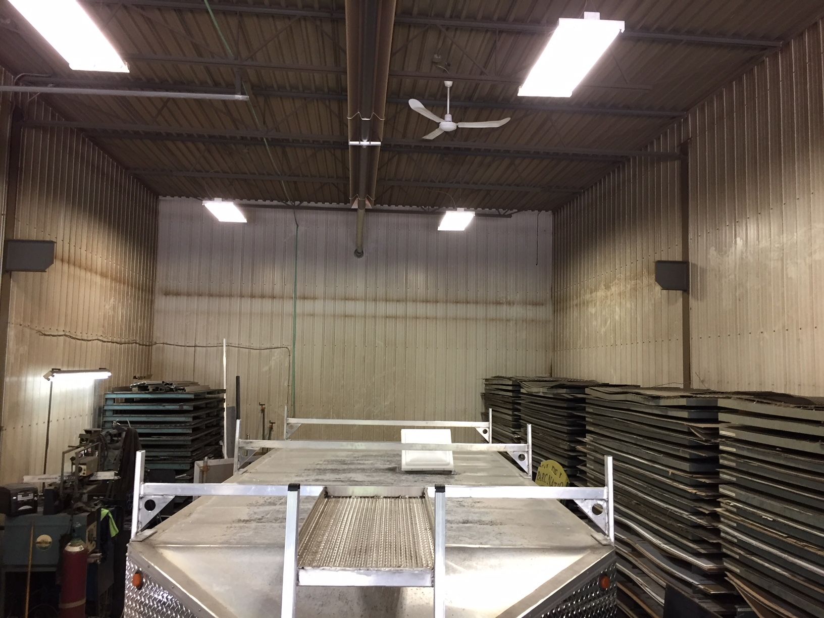 Workshop interior with a truck bed, stacked materials, and ceiling fan.