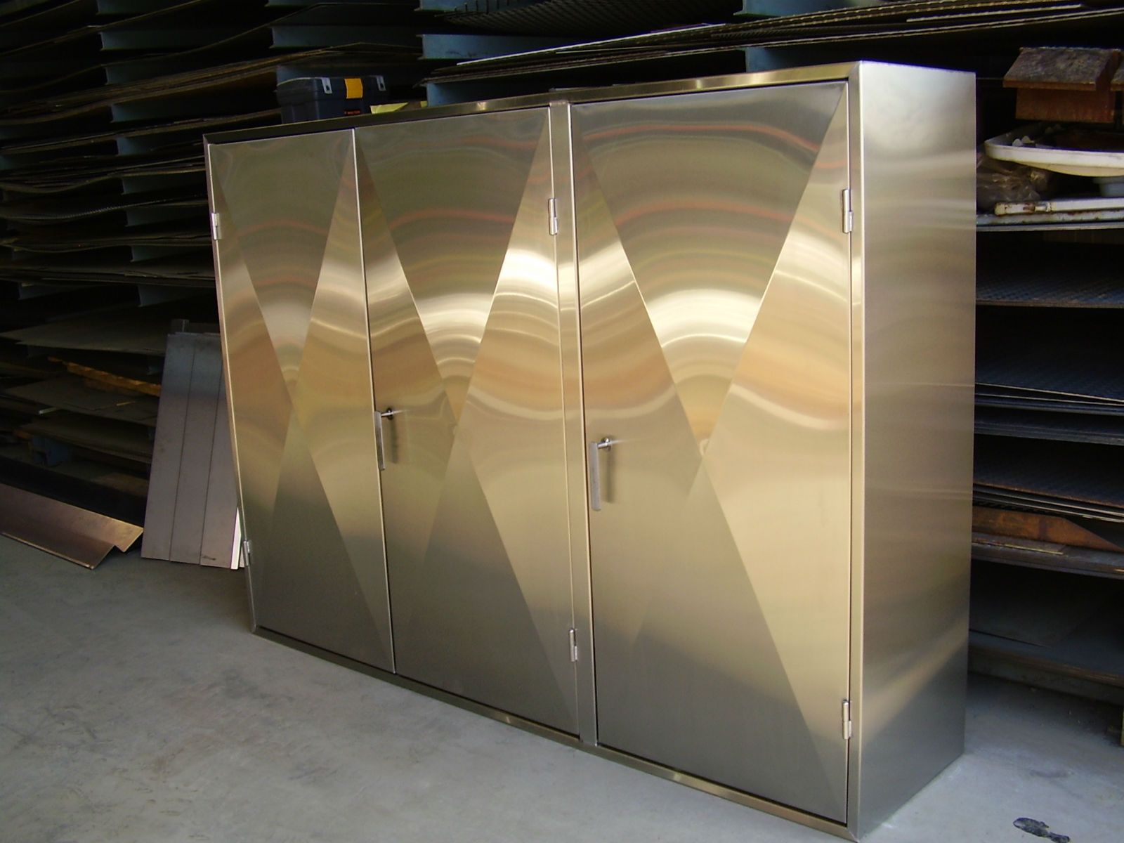 Three stainless steel cabinets with geometric designs; in a workshop.
