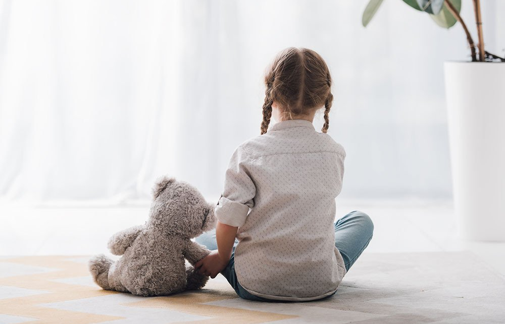 young child sitting with her teddy bear
