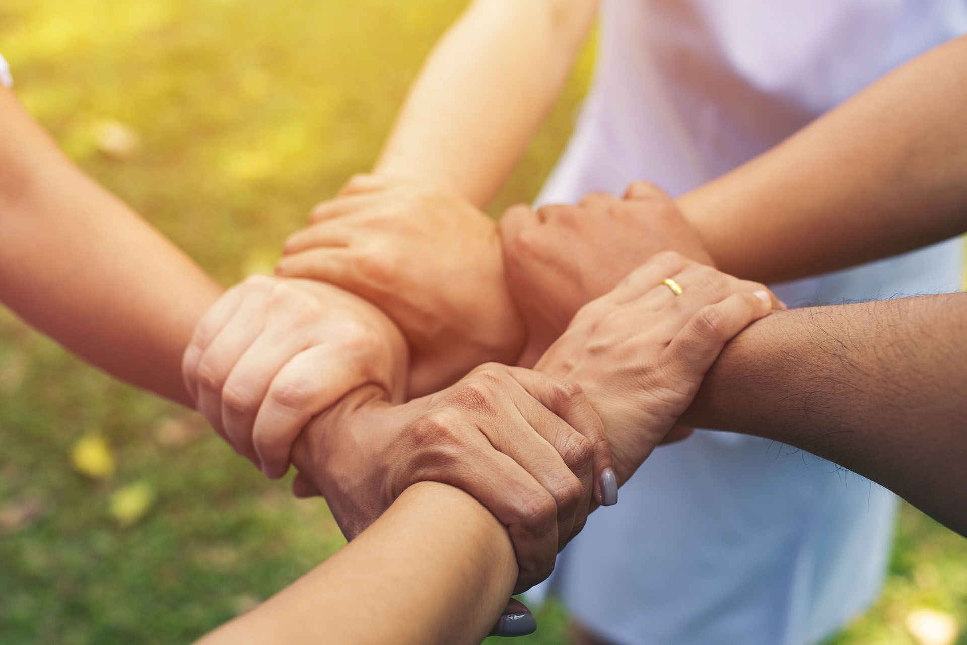 A group of people are putting their hands together in a circle.