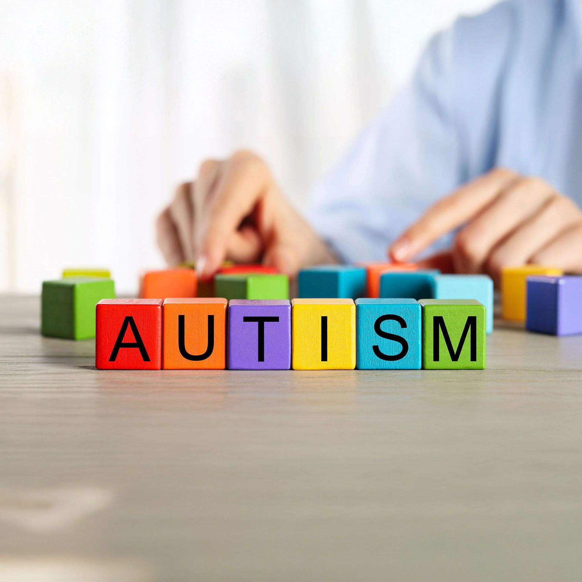 A child is playing with colorful wooden blocks that spell out the word autism.