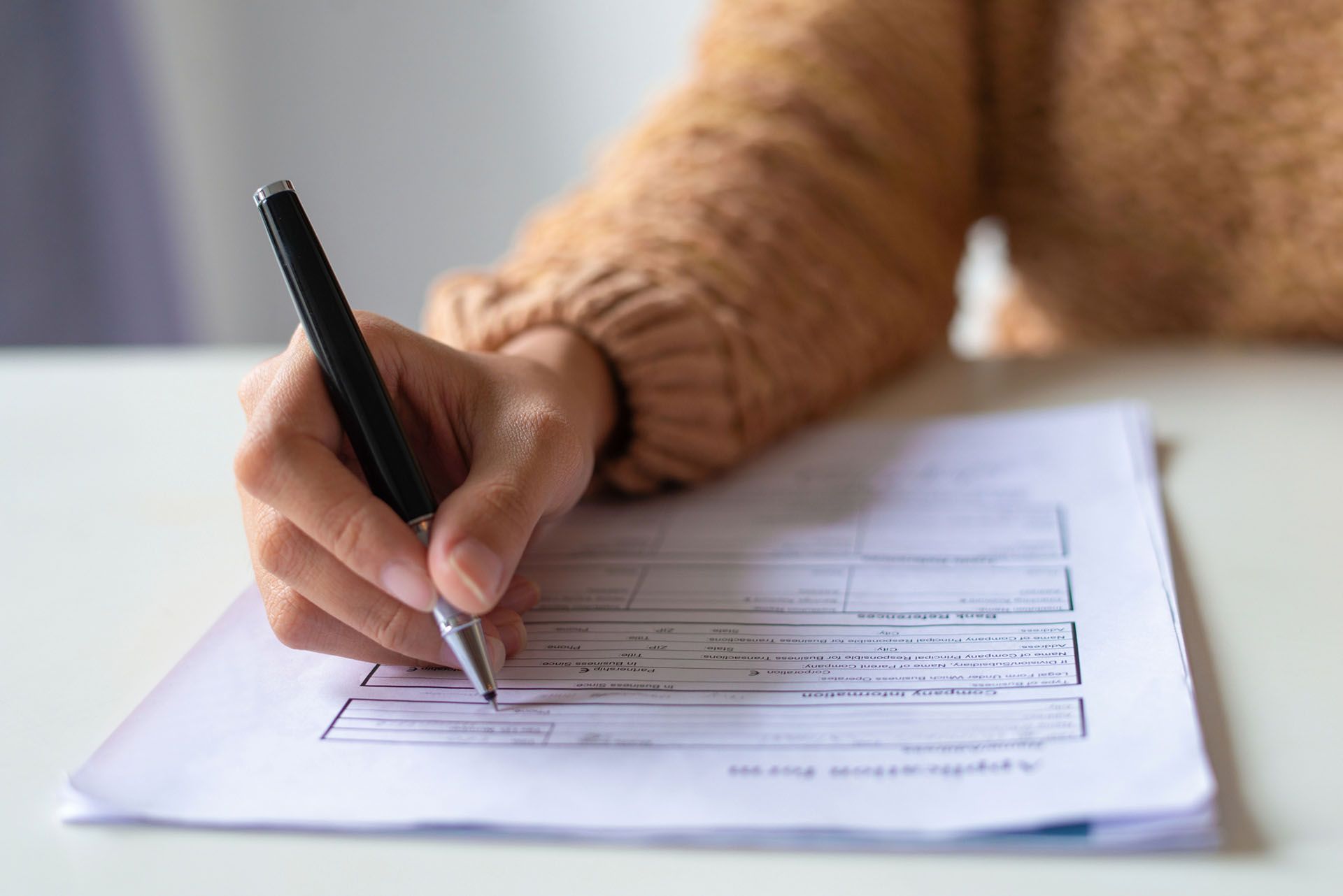 A person is writing on a piece of paper with a pen.