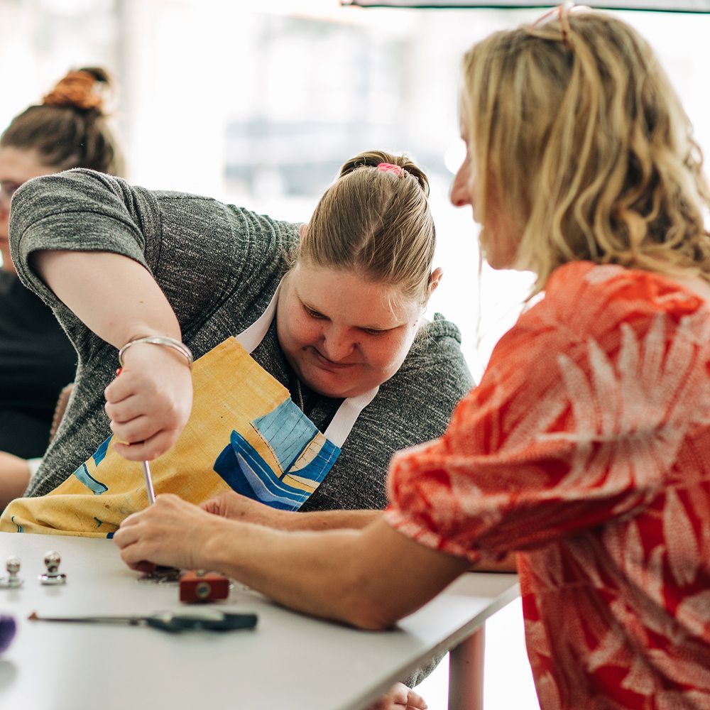 Two women are sitting at a table working on a project