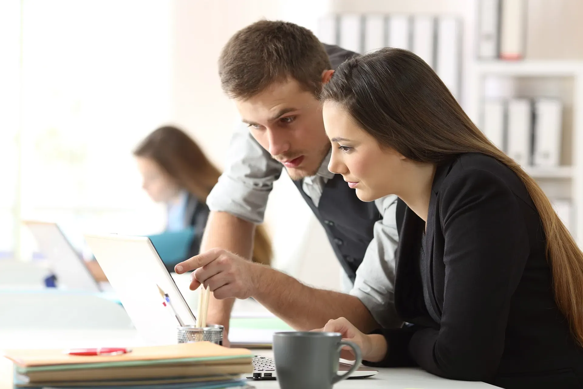 A man and a woman are looking at a laptop computer.