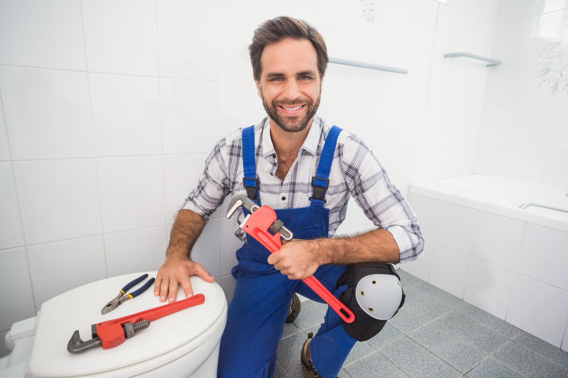 plumber holding a wrench and the toilet bowl