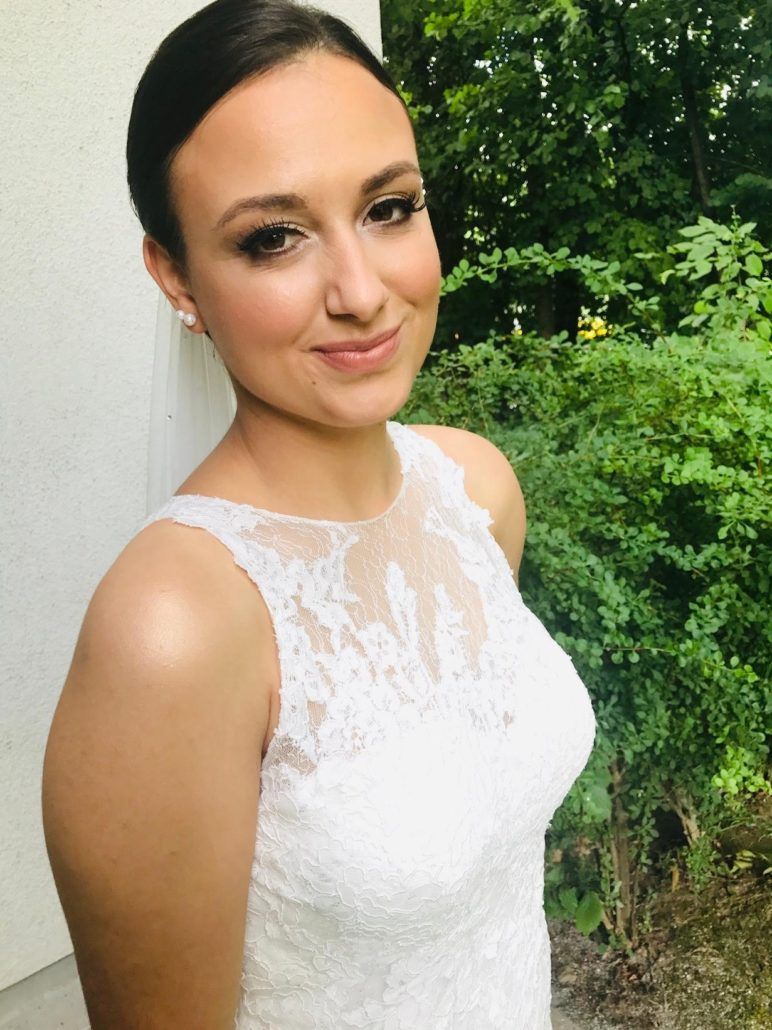 Eine Frau in einem weißen Kleid steht vor einem Busch.