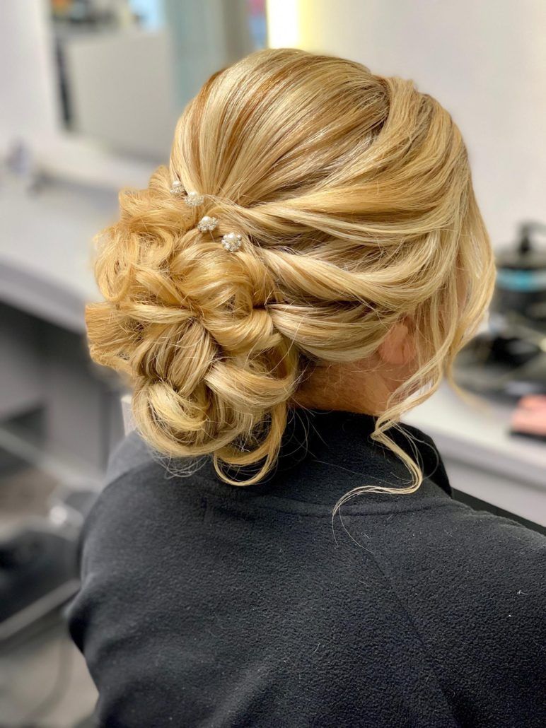 Eine Frau sitzt auf einem Stuhl und hat die Haare zu einem Knoten zusammengebunden.