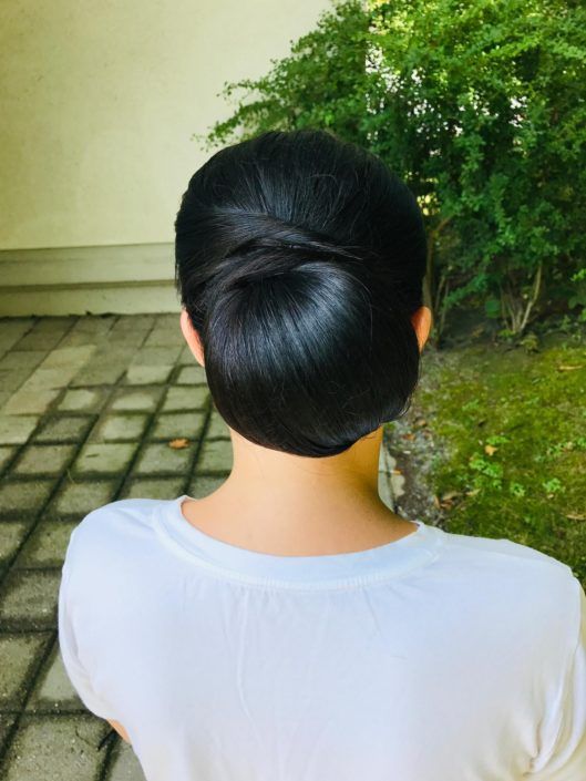 Eine Frau mit einem Haarknoten steht auf einem Bürgersteig.