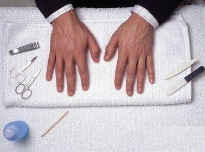 Ein Mann lässt sich an einem Handtuch die Nägel machen.