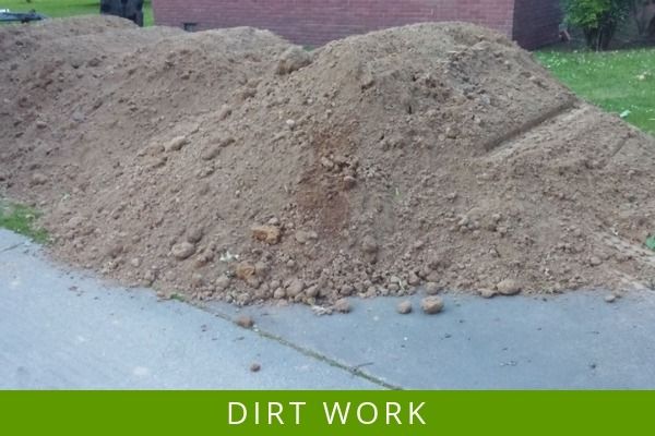 Large dirt pile on a roadside with green grass and a “DIRT WORK” label below