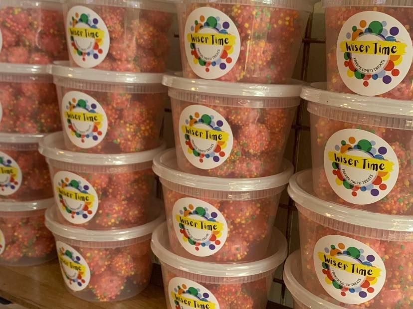 A bunch of plastic containers filled with candy are stacked on top of each other on a table.