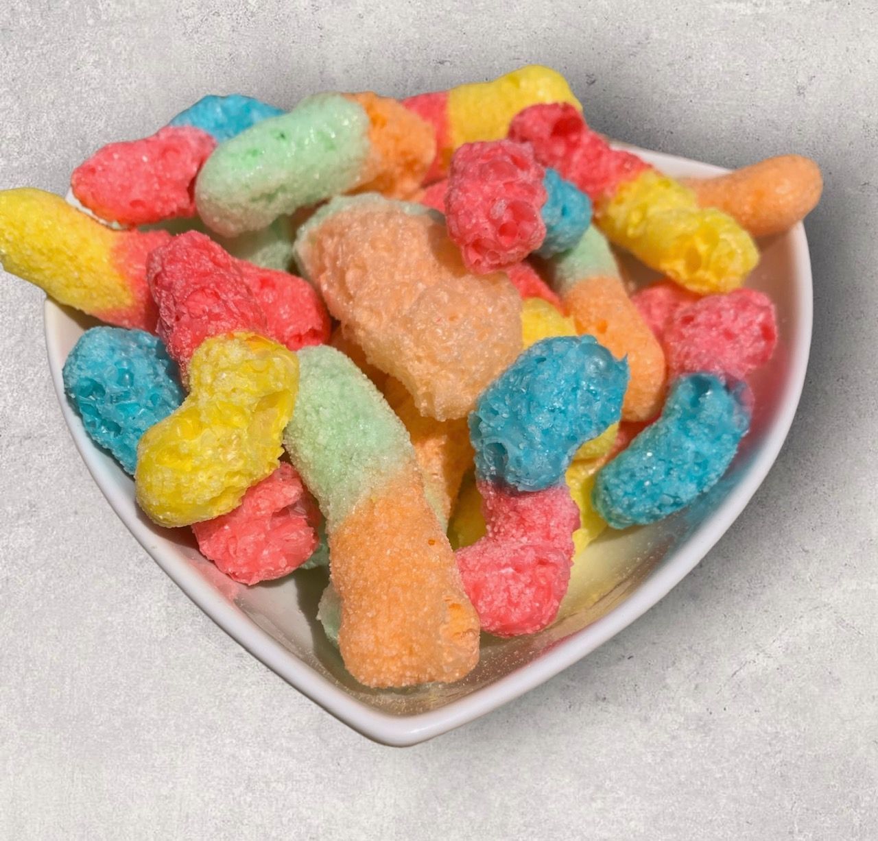 A heart shaped bowl filled with colorful cereal puffs