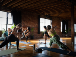 Yoga class stretching in a sunlit studio with brick walls and wooden floors