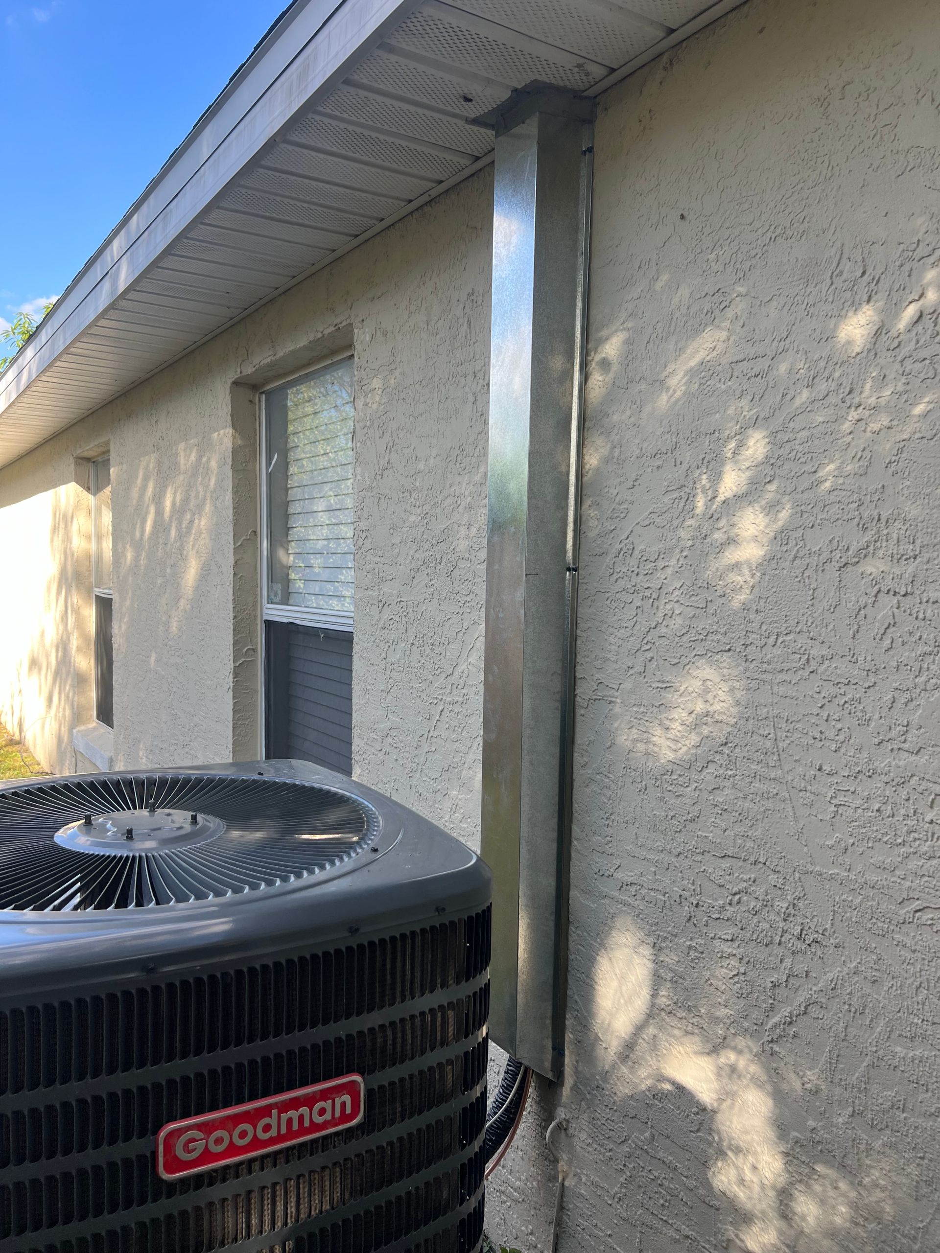 a goodmans air conditioner is sitting on the side of a house .