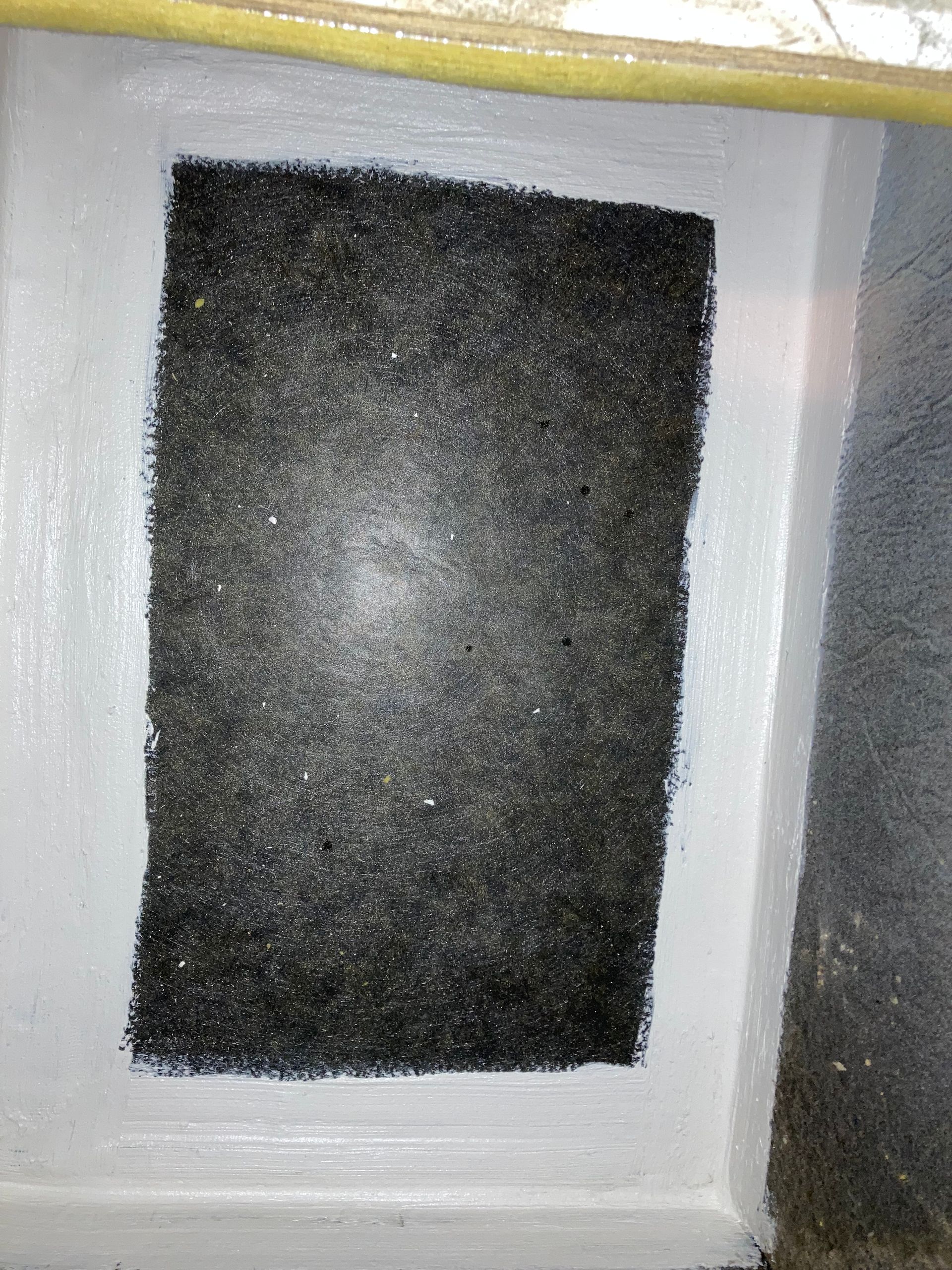 a black sponge is sitting on a white surface .