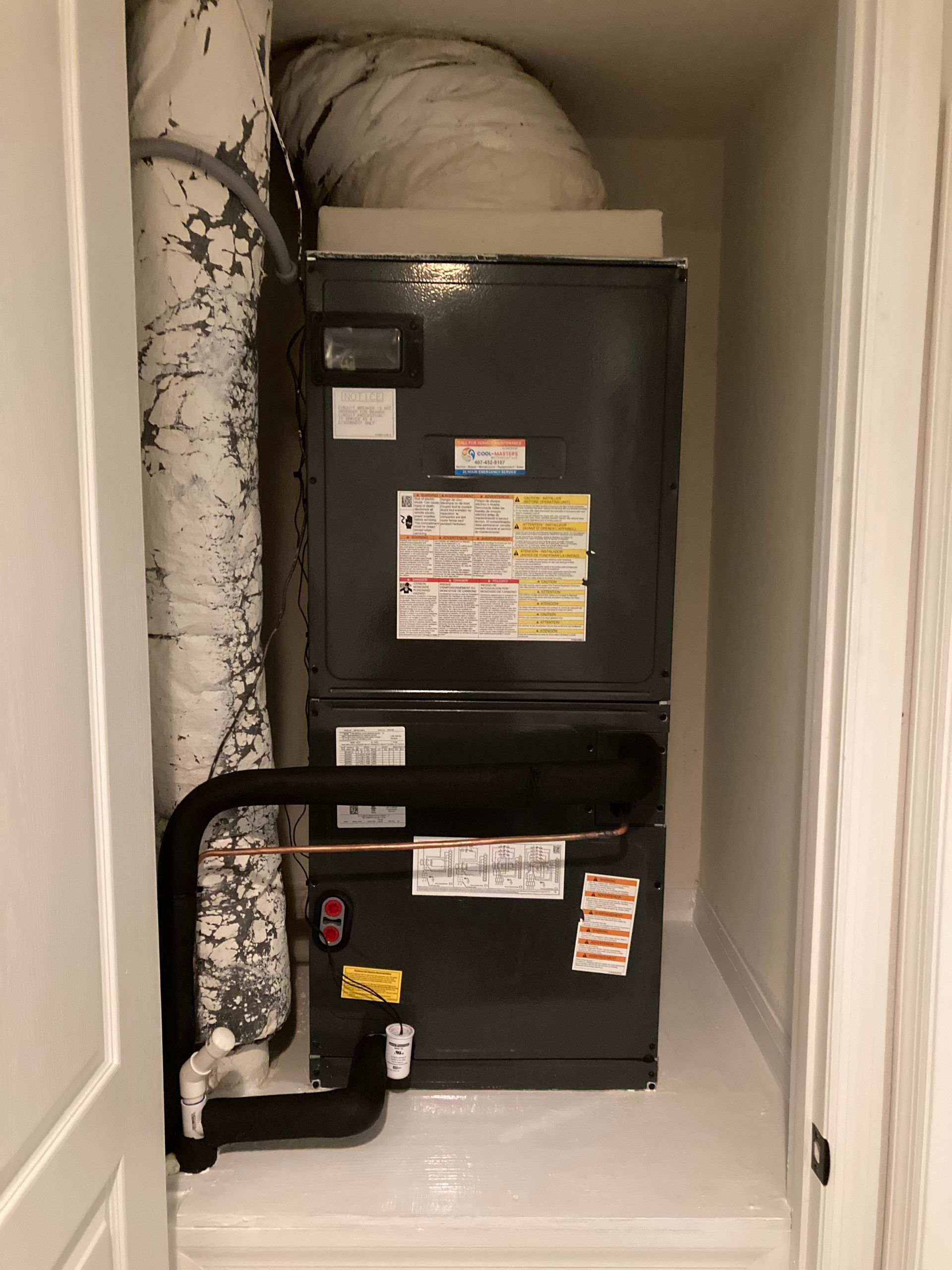 an air conditioner is sitting in a closet next to a pipe .