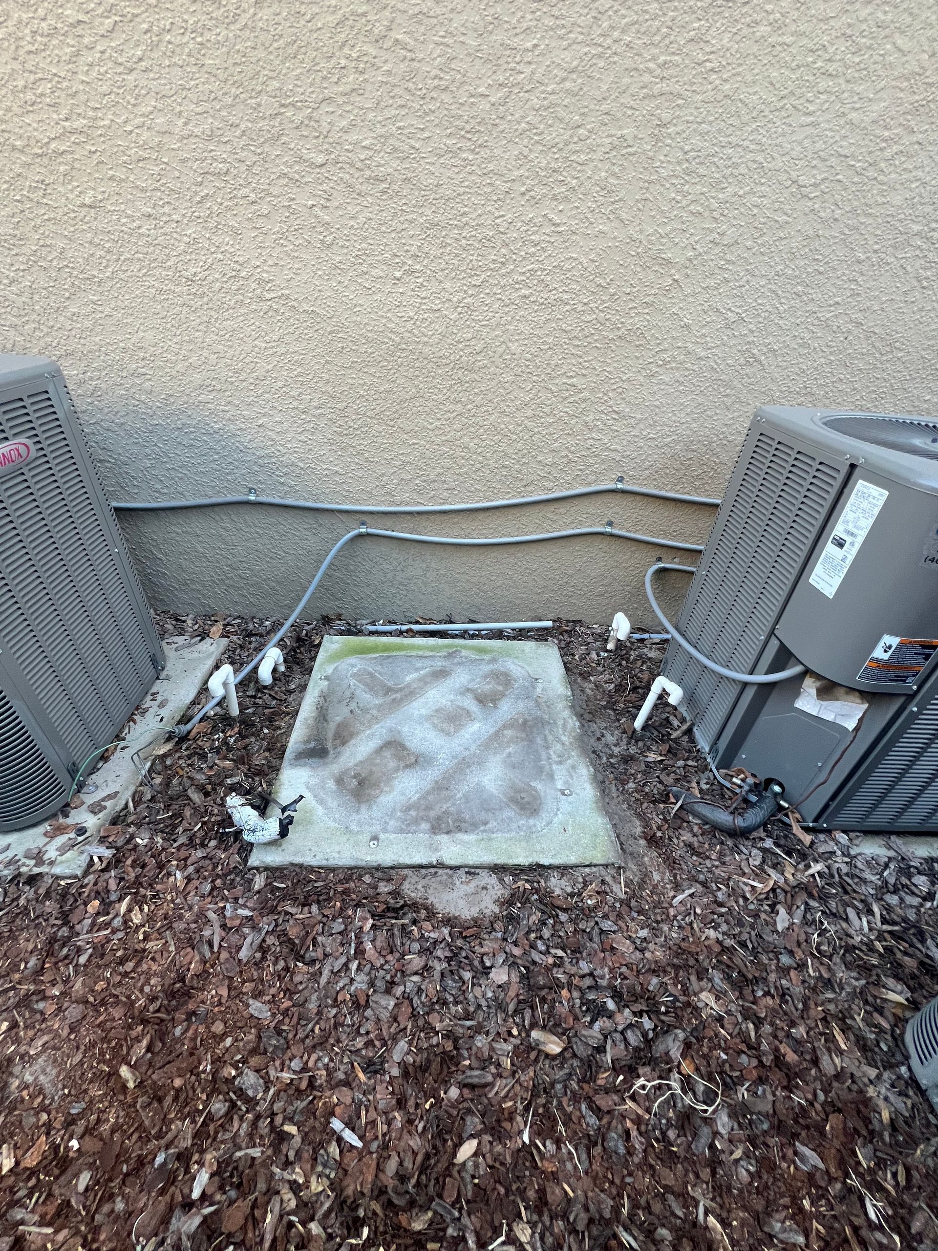 a couple of air conditioners sitting on top of a pile of mulch .