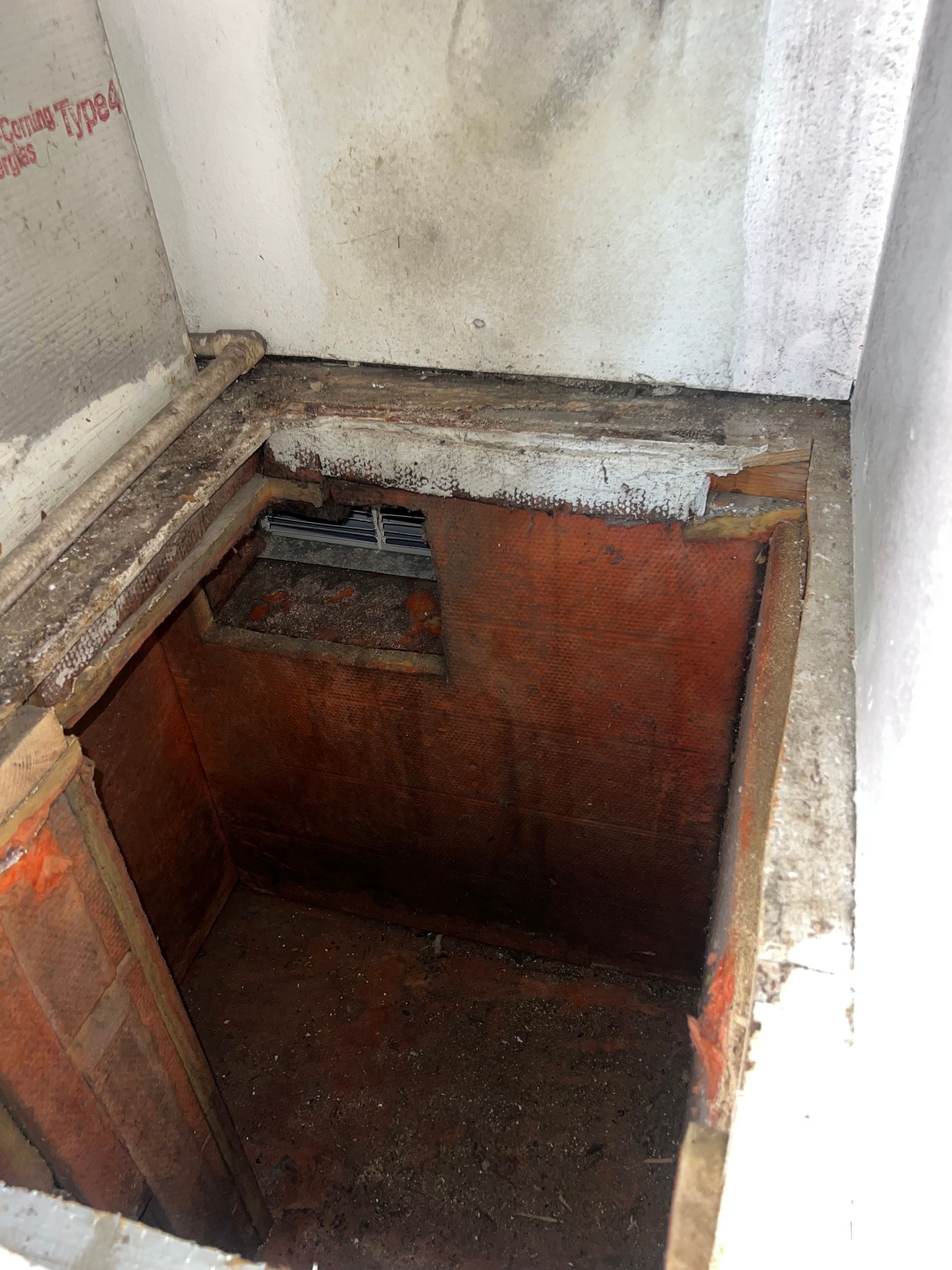 a dirty room with a hole in the wall and a wooden door .