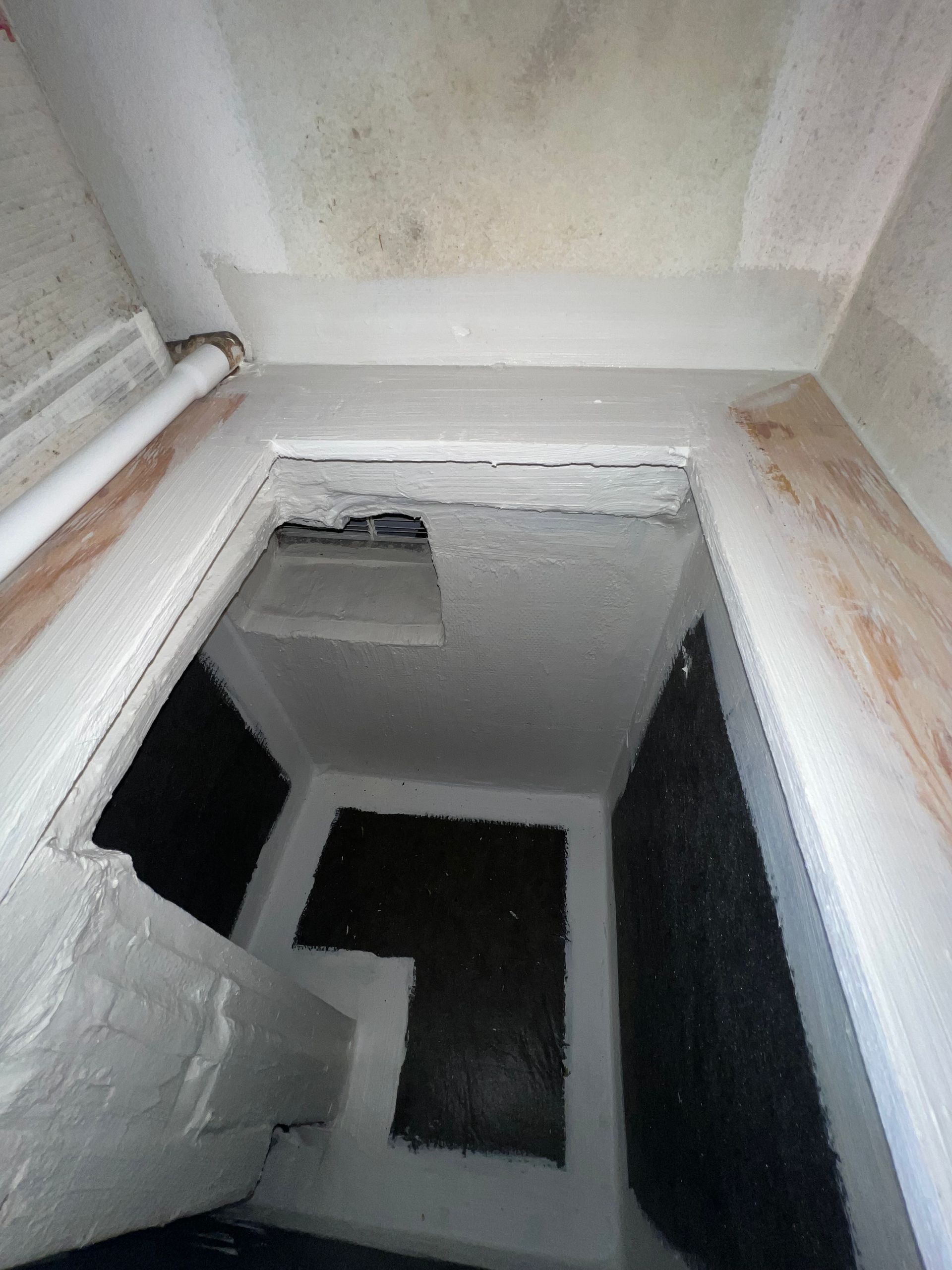 a small room with a white wall and a black rug on the floor .