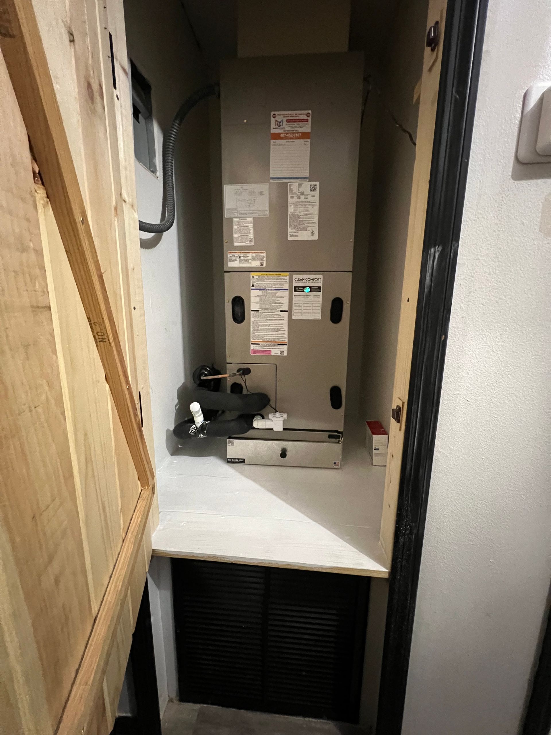 an air conditioner is sitting in a closet next to a door .