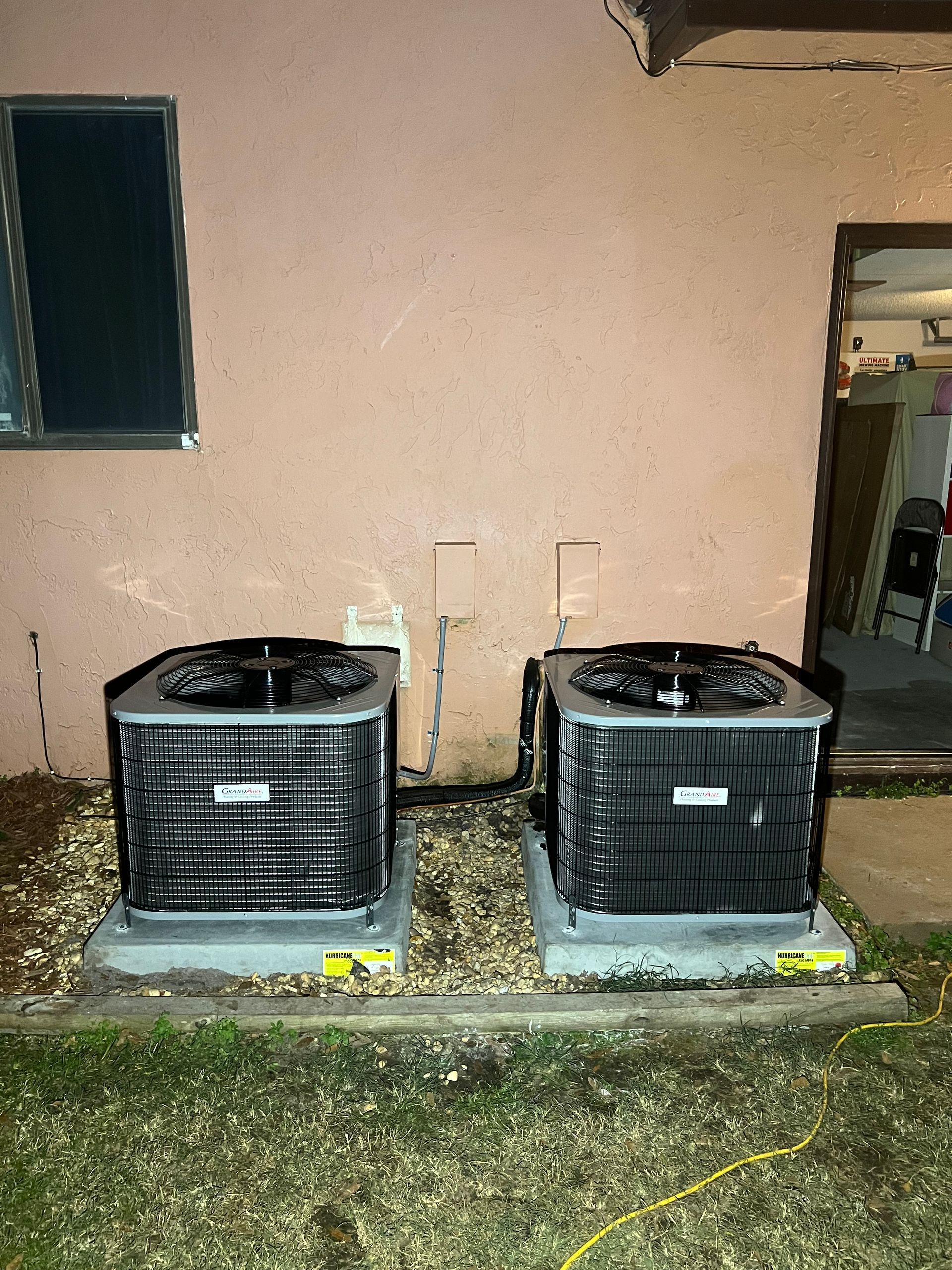 two air conditioners are sitting next to each other on the side of a building .