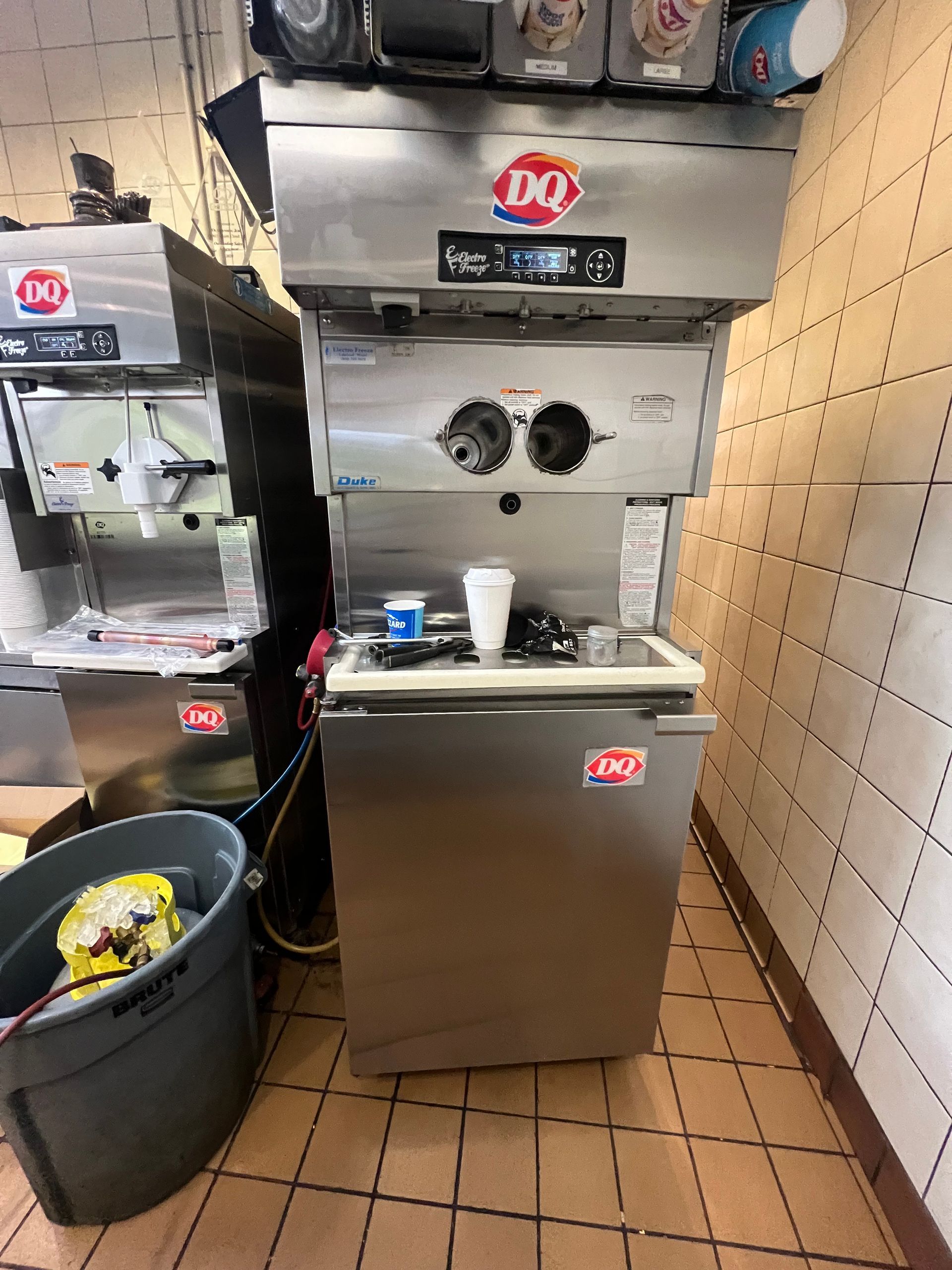 a dairy queen ice cream machine is sitting in a kitchen next to a trash can .