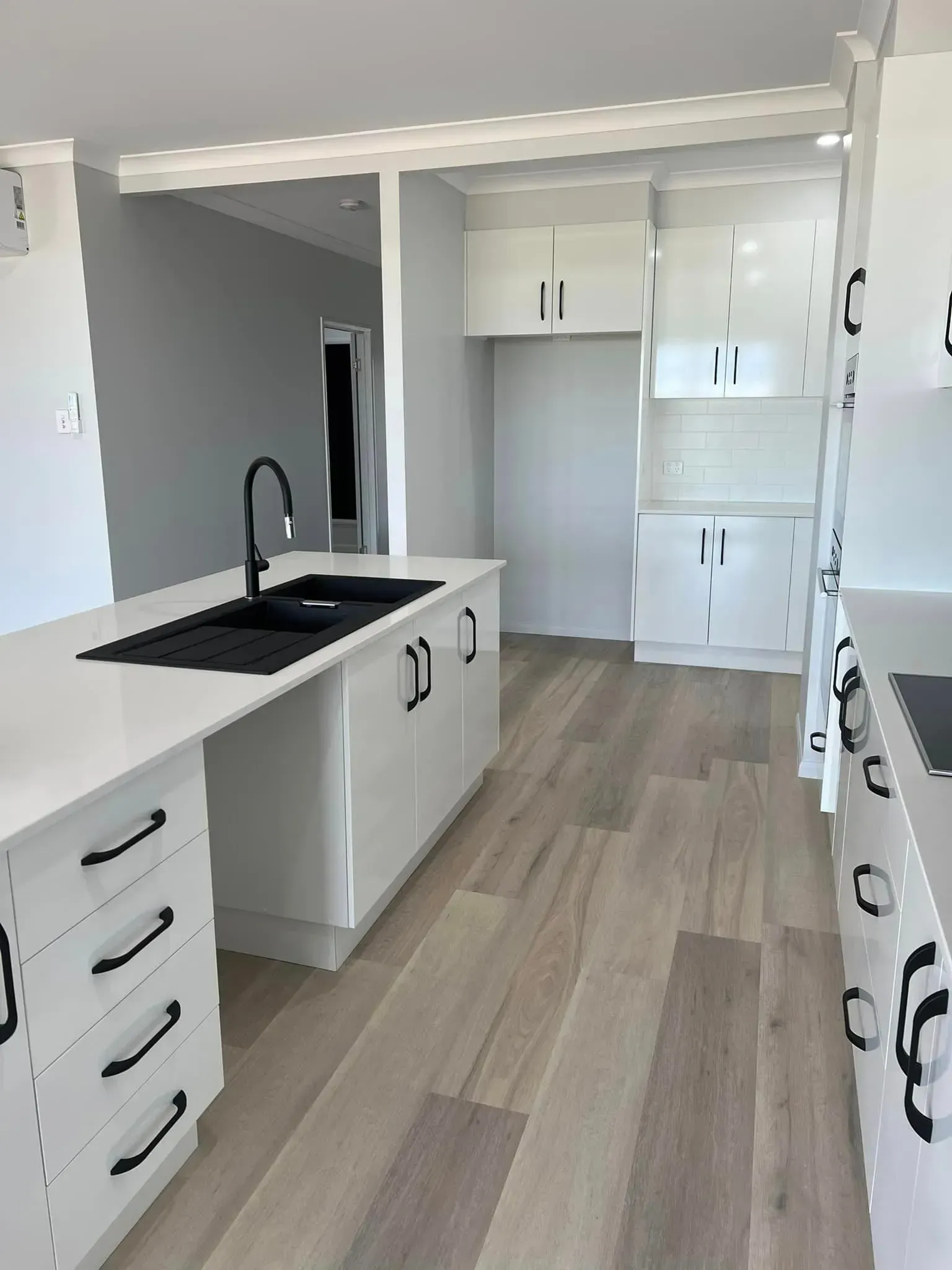 A Kitchen With White Cabinets And Hardwood Floors And A Sink — Reynolds Built In Dicky Beach, QLD