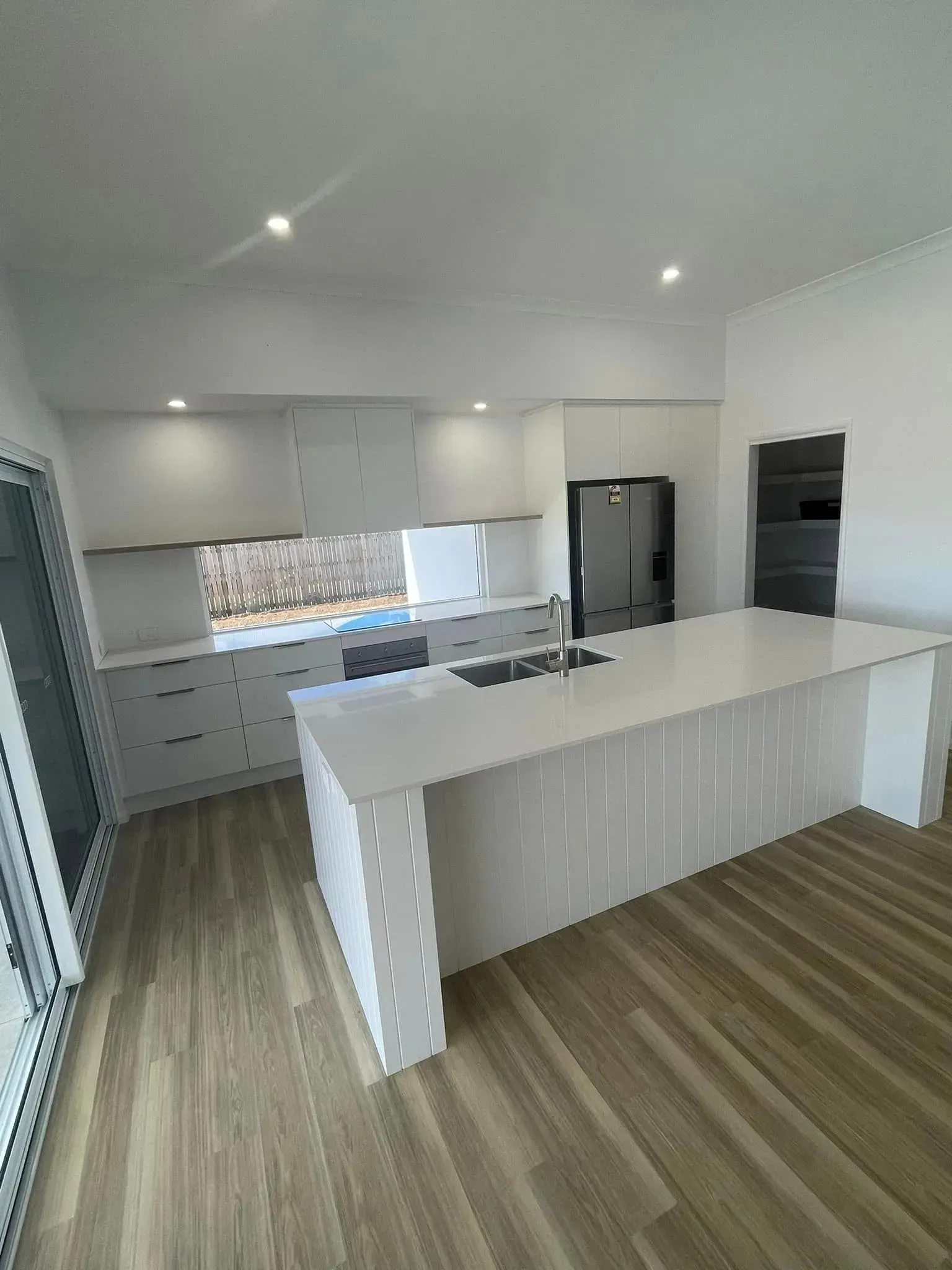 A Kitchen With White Cabinets And A Large Island In The Middle — Reynolds Built In Dicky Beach, QLD