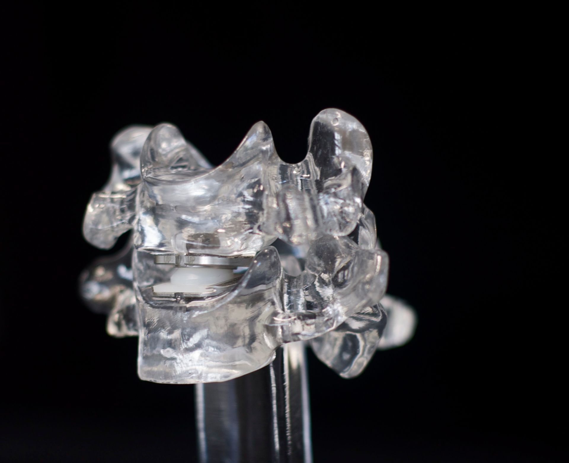 A close up of a clear plastic object on a black background.