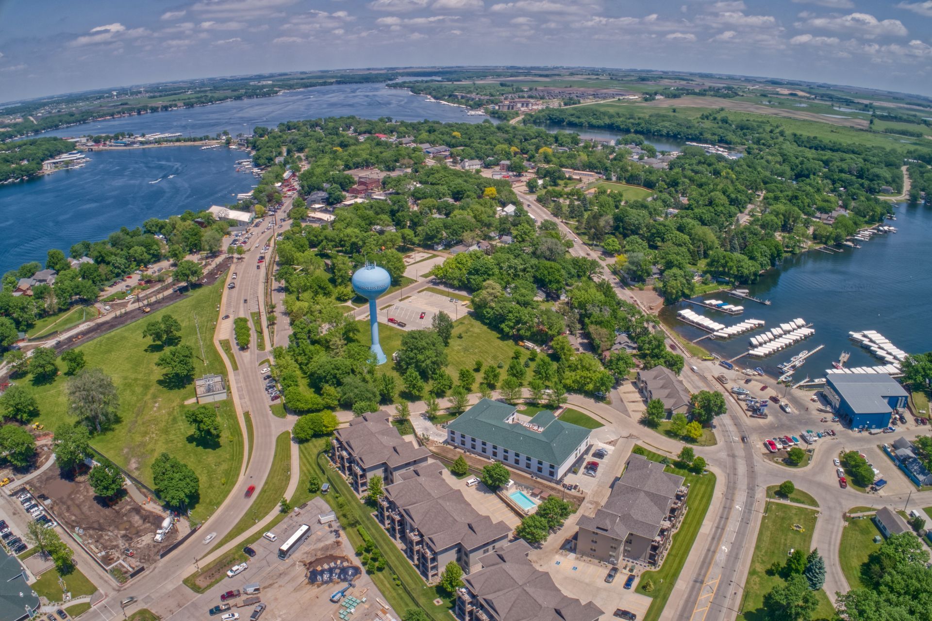 Aerial view of a town with a blue water tower, waterfront, buildings, roads, and trees.