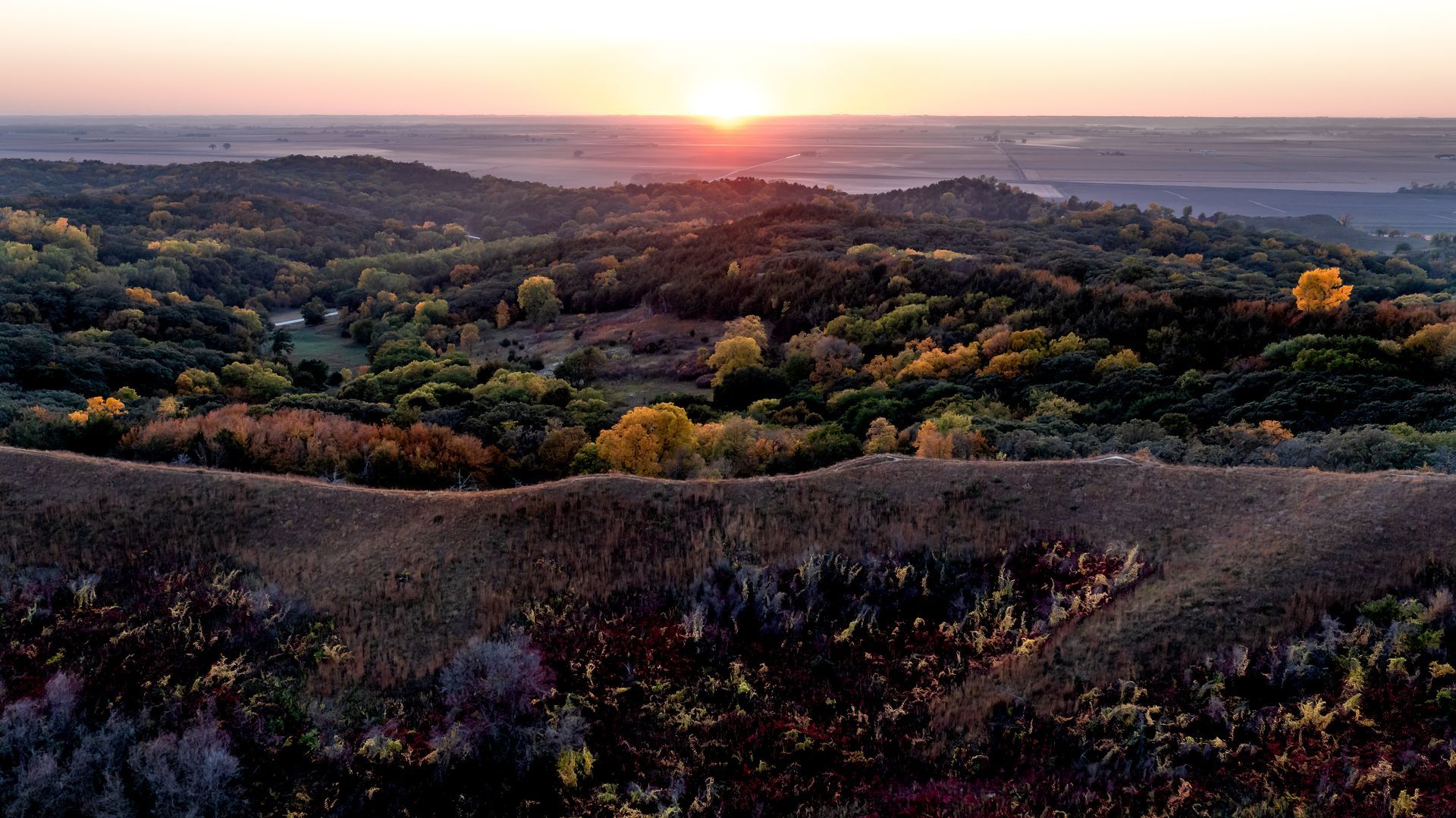 Sunset over forested hills with autumn colors.